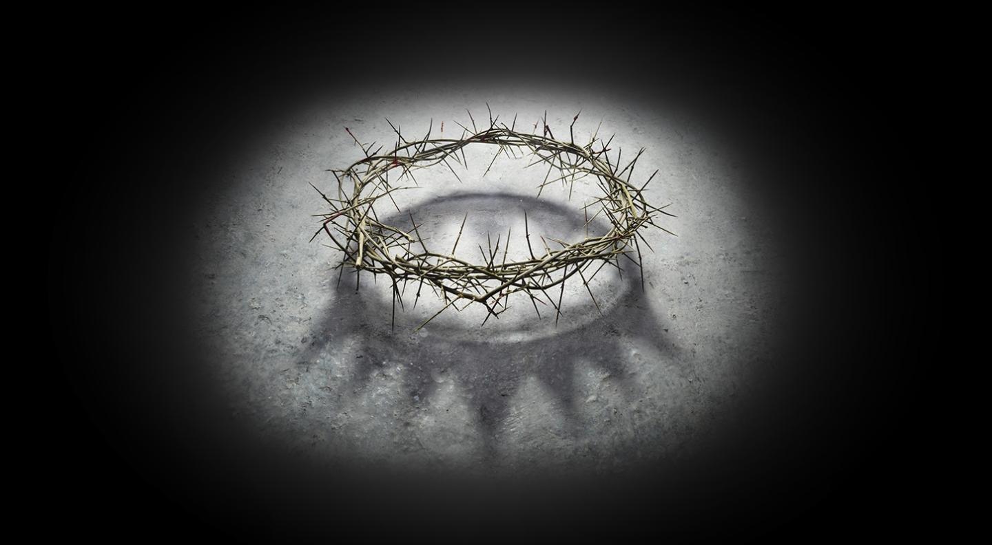 An artistic image of a crown of thorns surrounded by a white light on a black background
