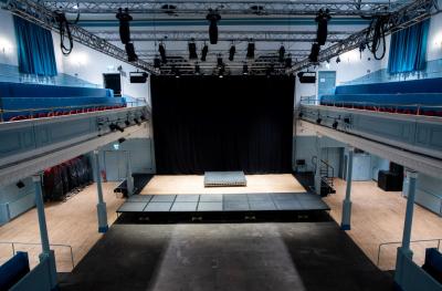 A view from above of a stage with a black backdrop and a bare stone floor infront