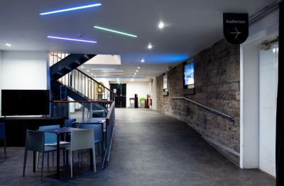 A view along a wide foyer with a door to the auditorium on the right hand side and tables and chairs on the left hand side. 