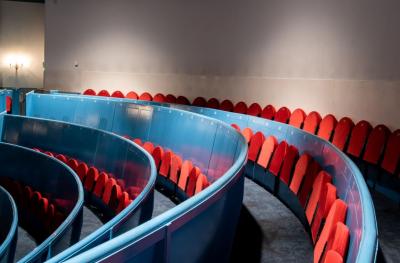 Curved rows of red flipdown seats with blue wooden backs