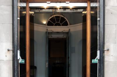 A large black and glass door stands open to show the inside of a building