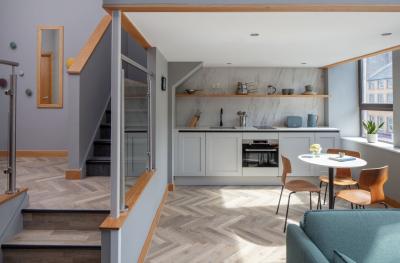 A kitchen diner with steps up the left and a herringbone wooden floor