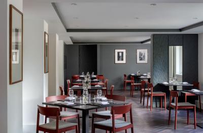 An empty dining room with grey and white walls and brown tables and chairs laid out for a meal