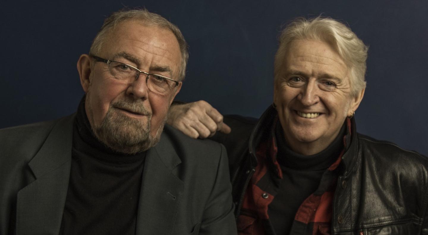 an image of Aly Bain and Phil Cunningham, two older white men with greying hair. They smile into the camera.