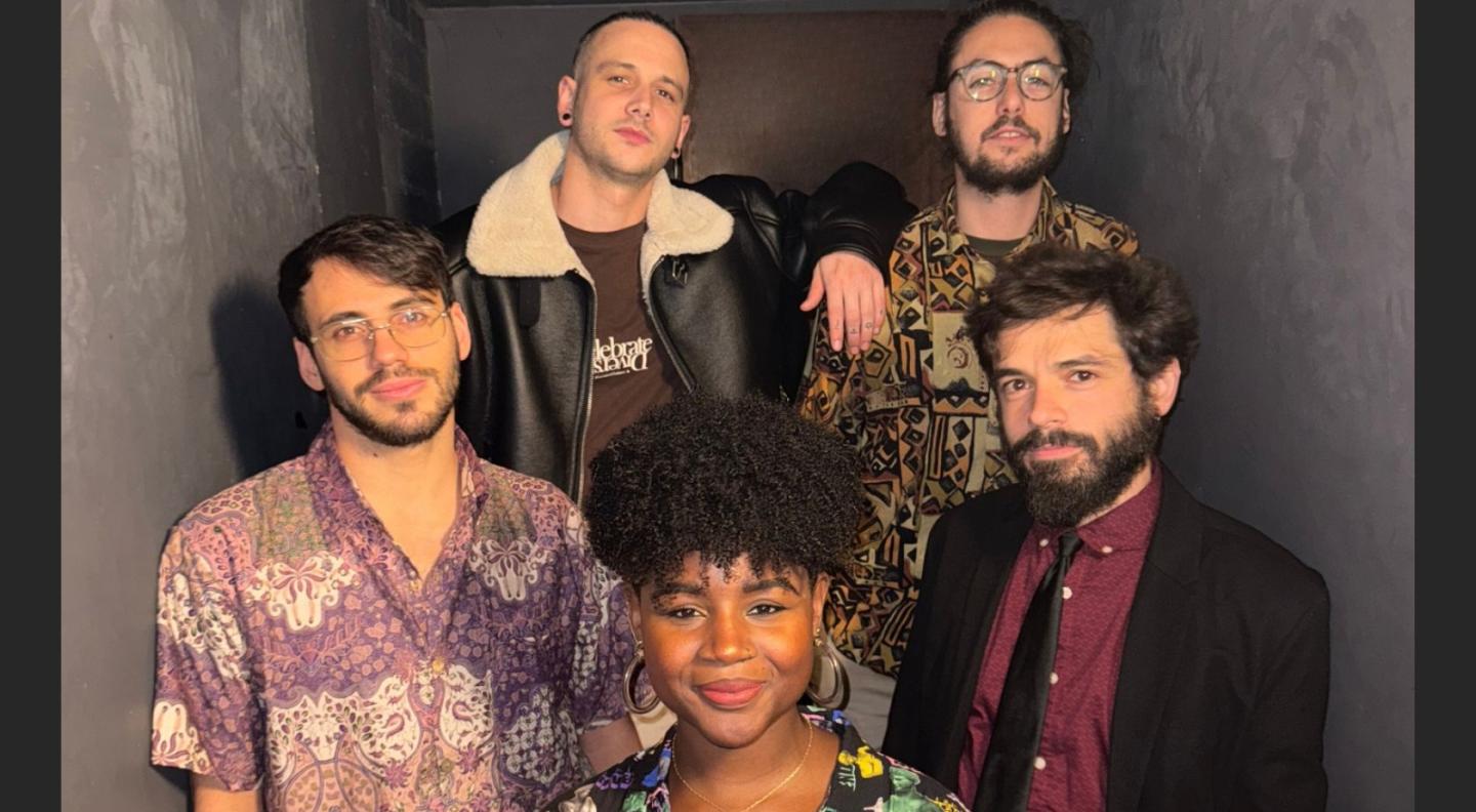 Five members of the band against a grey background
