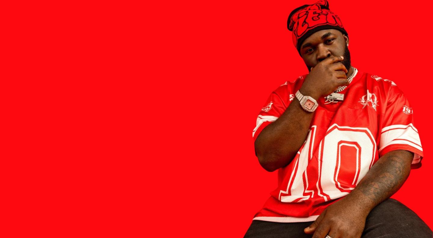 Pillz the Energiser wearing a red American Football top, sitting in front of a red background