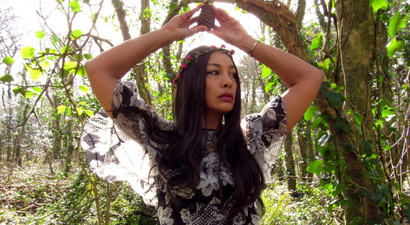 A photograph of Angeline Morrison holding a pinecone above her head
