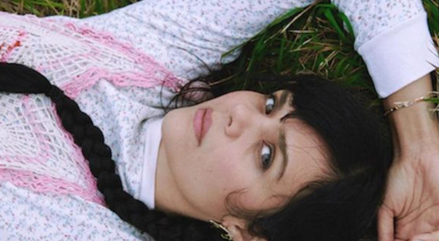A woman with a long dark braind lies on grass