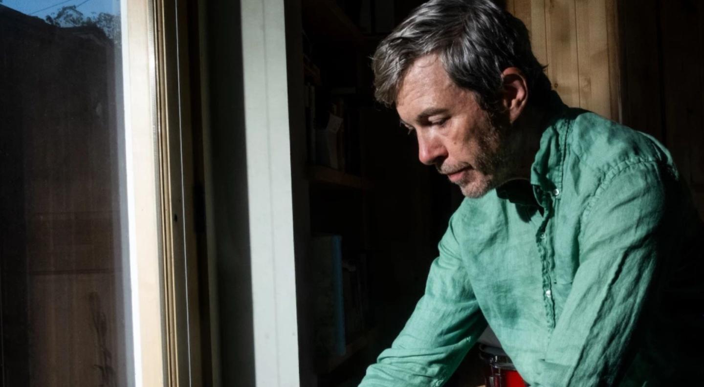 bill callahan in green shirt looking down thoughfully