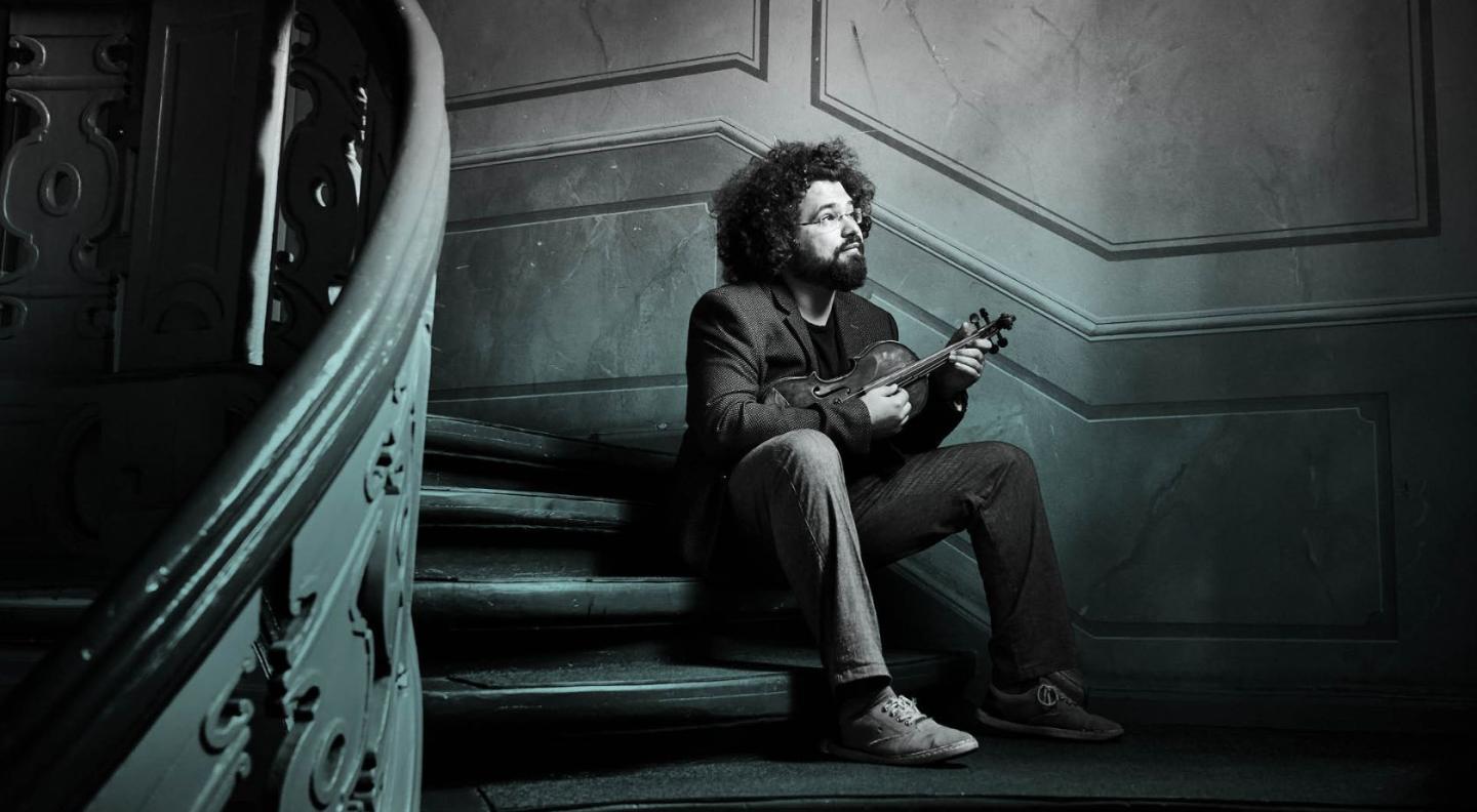 A man sitting on the stairs with a violin