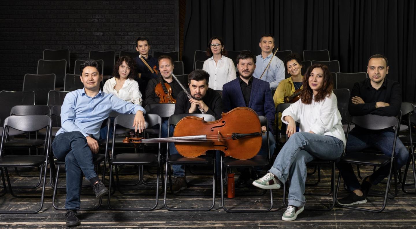 A group shot of the Eegeru Ensemble - 10 young men and women - sitting lookiing at the camera