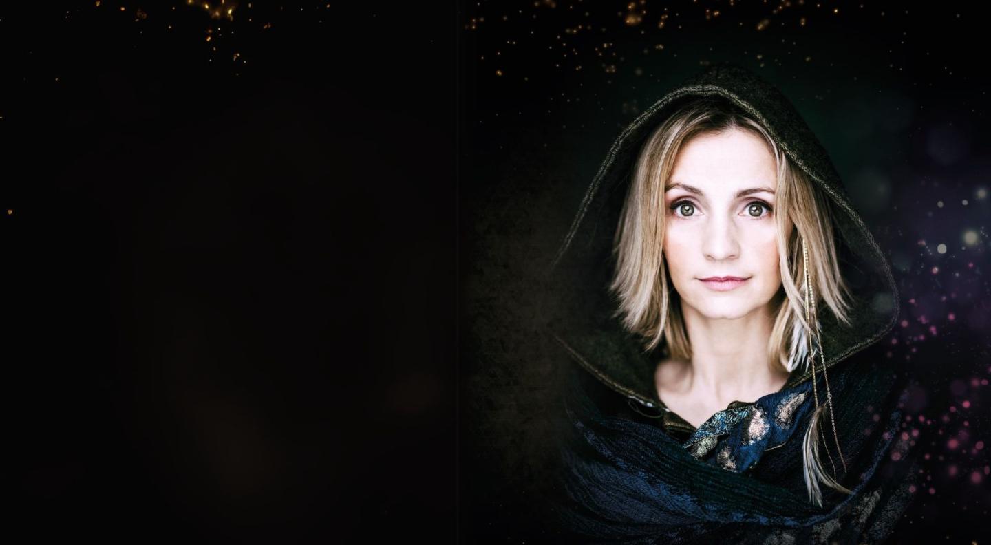 Folk singer Cara Dillon wearing a hood against a black background