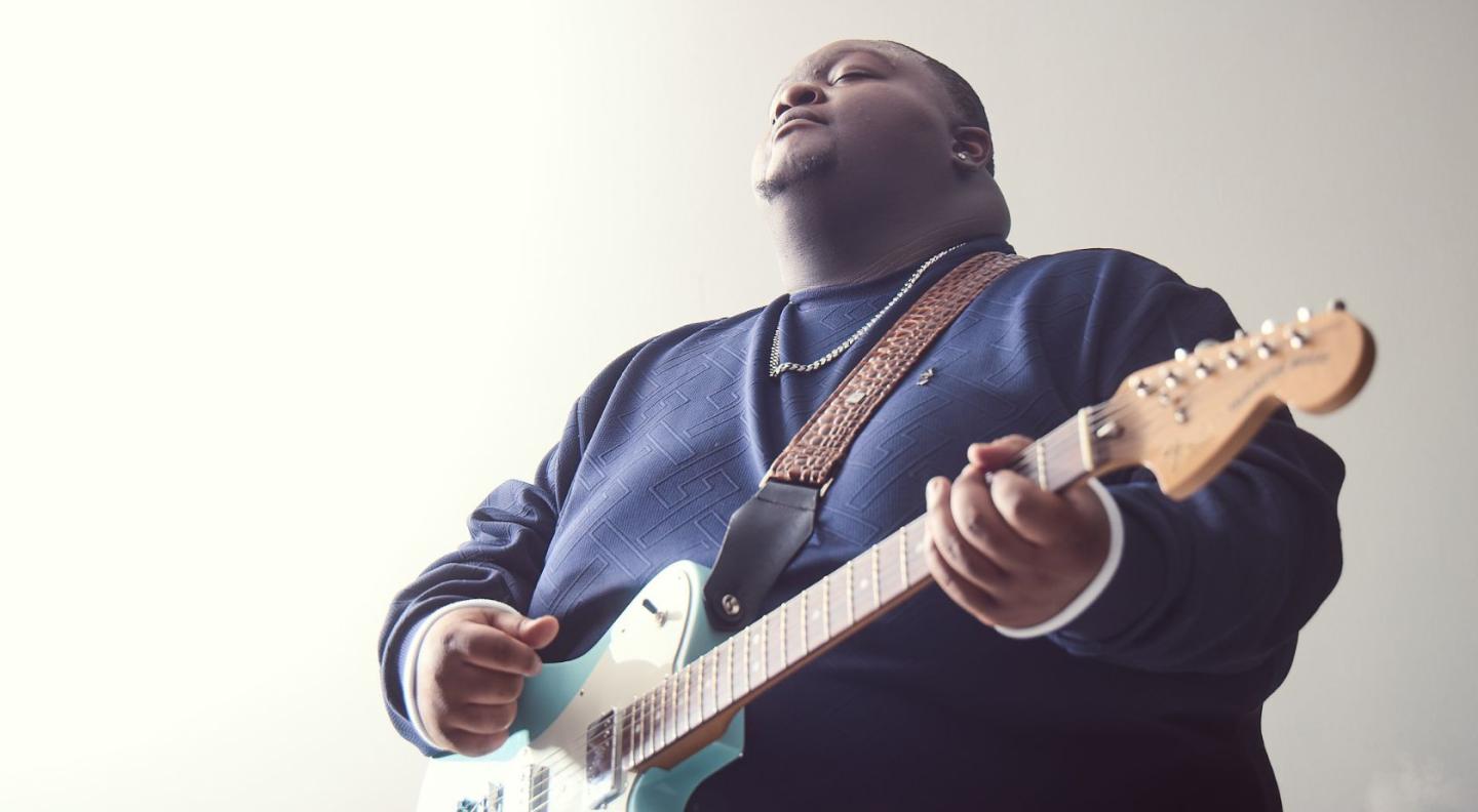 A photo of Christone Kingfish Ingram playing the guitar