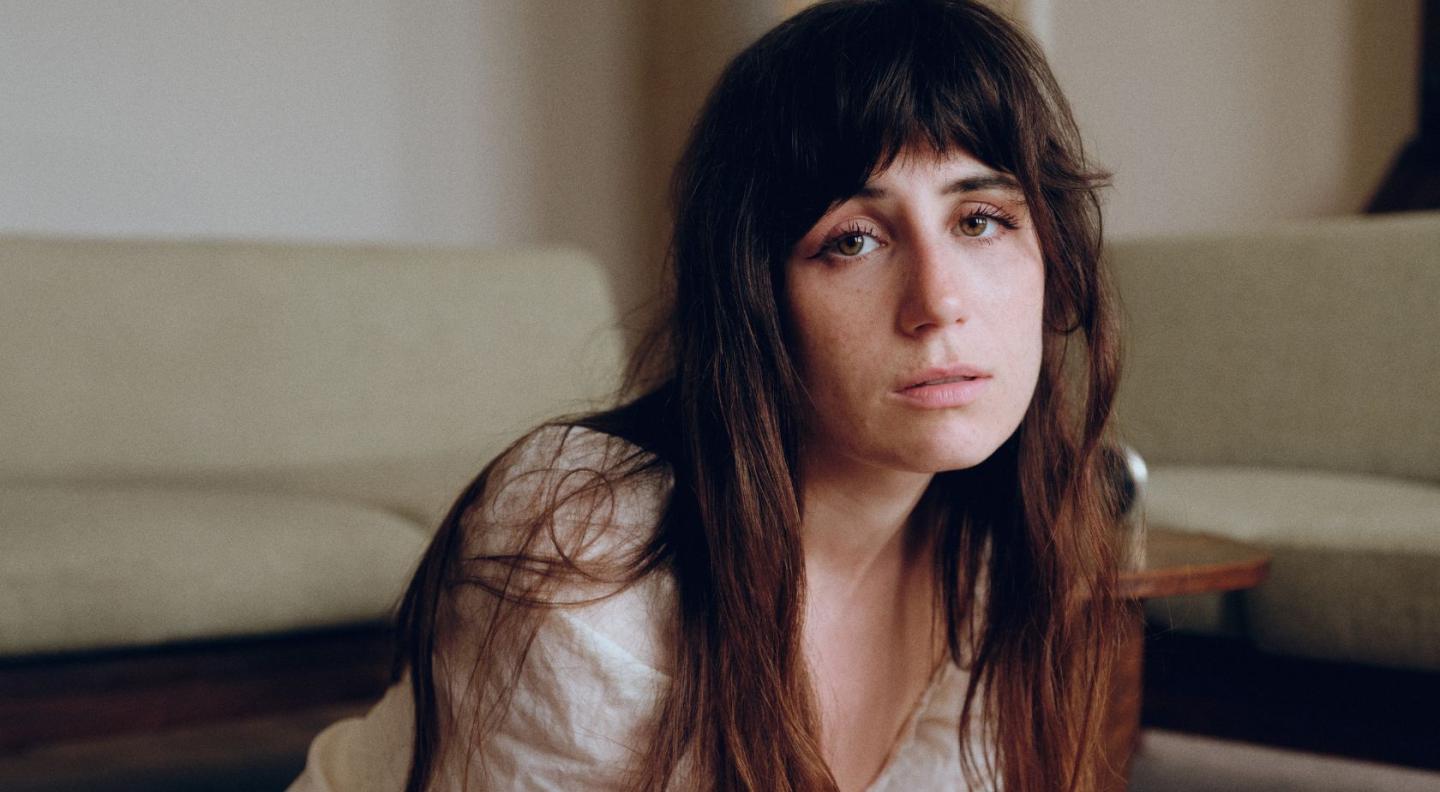 Dodie, a white woman with long brown hair and a fringe, looking at the camera