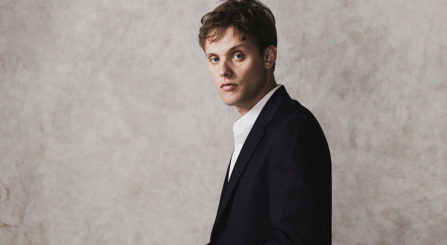 Alexander Chance standing in front of a mottled white and grey background