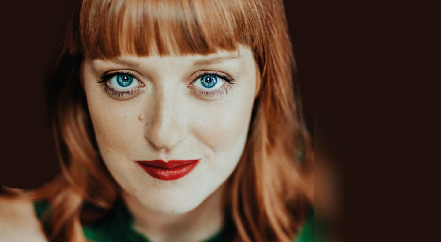 A headshot of Carine Tinney against a black background
