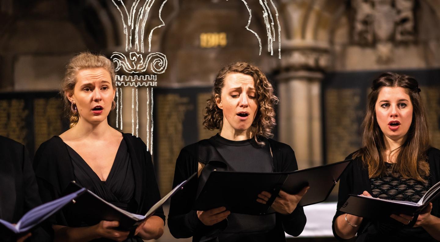 Three women stand singing in front of arches in a church