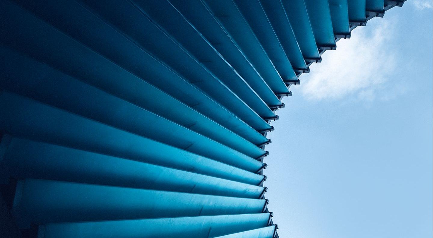 an image looking up at a building with blue panels, arranged like a staircase