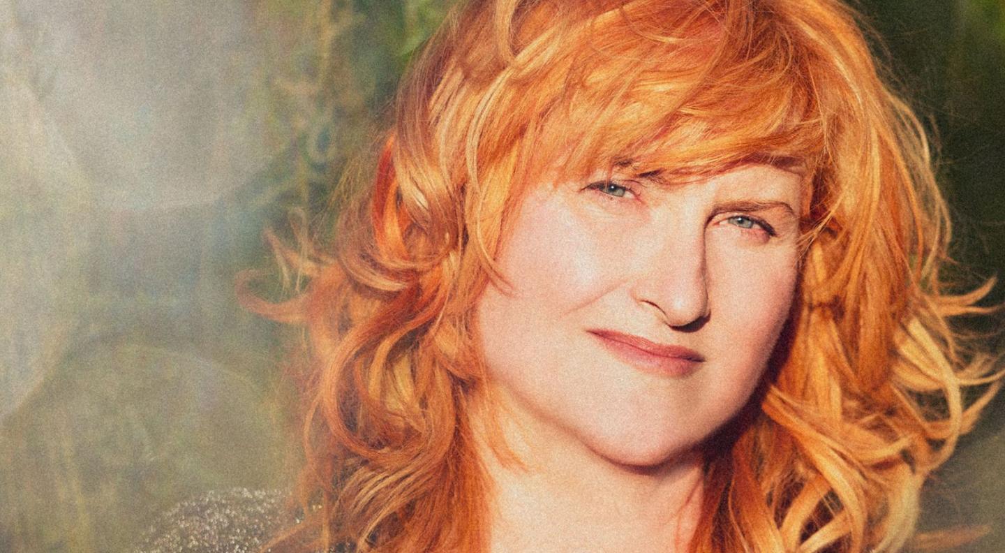 A photograph of Eddi Reader, a white woman with ginger hair, smiling at the camera