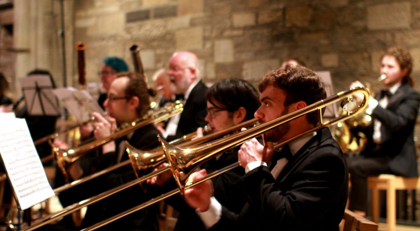 Edinburgh City Orchestra brass section in smart dress playing the trombone