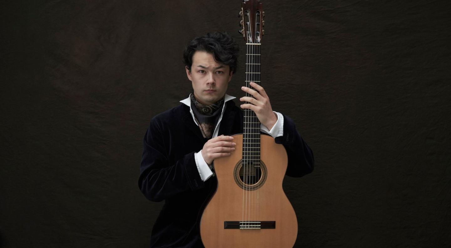 Sean Shibe holding his guitar