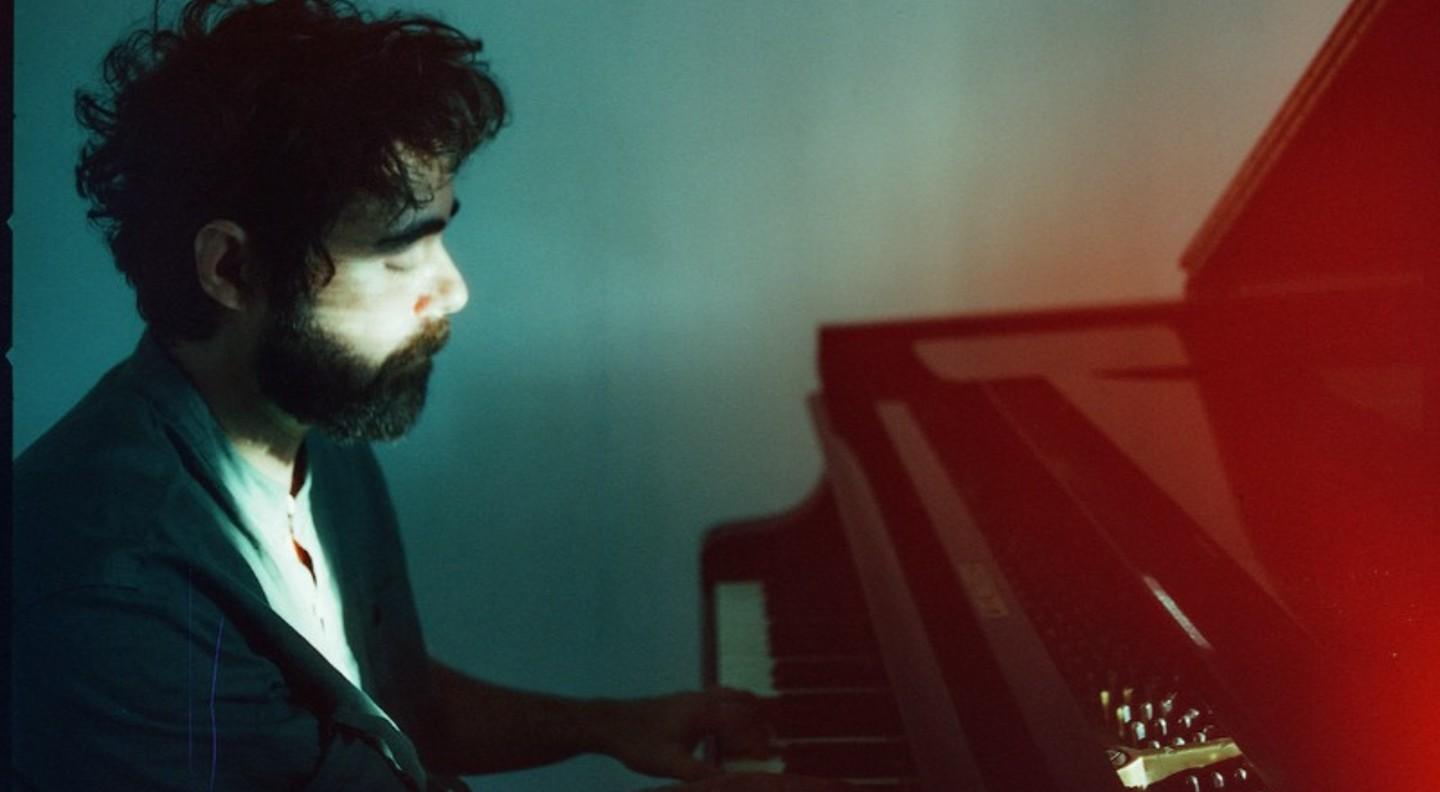 A side-on midshot of Federico Albanese seated at the piano