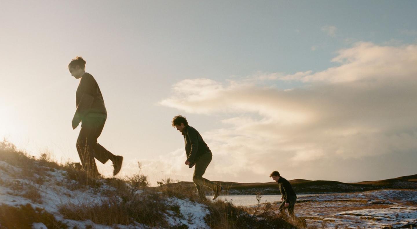 The three members of the Fergus McCreadie Trio running up a hill