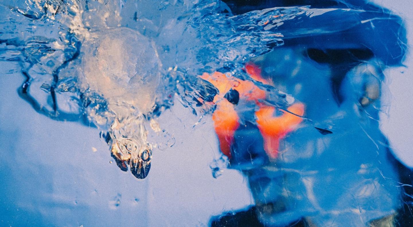 An impressionistic picture with Erland Cooper's face in blue tones blurred out by a long splash of water