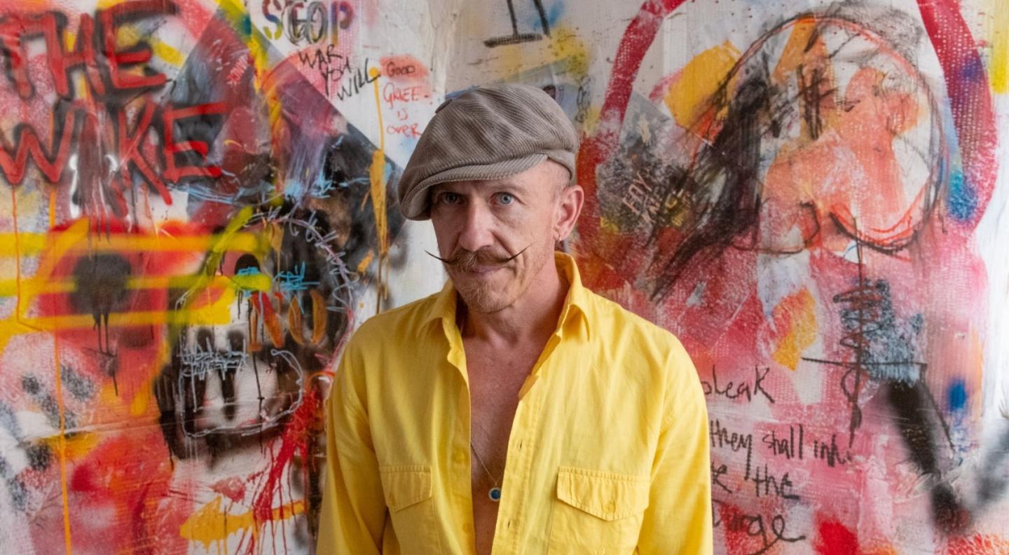 Foy Vance wearing a yellow shirt in front of a colourful painted background