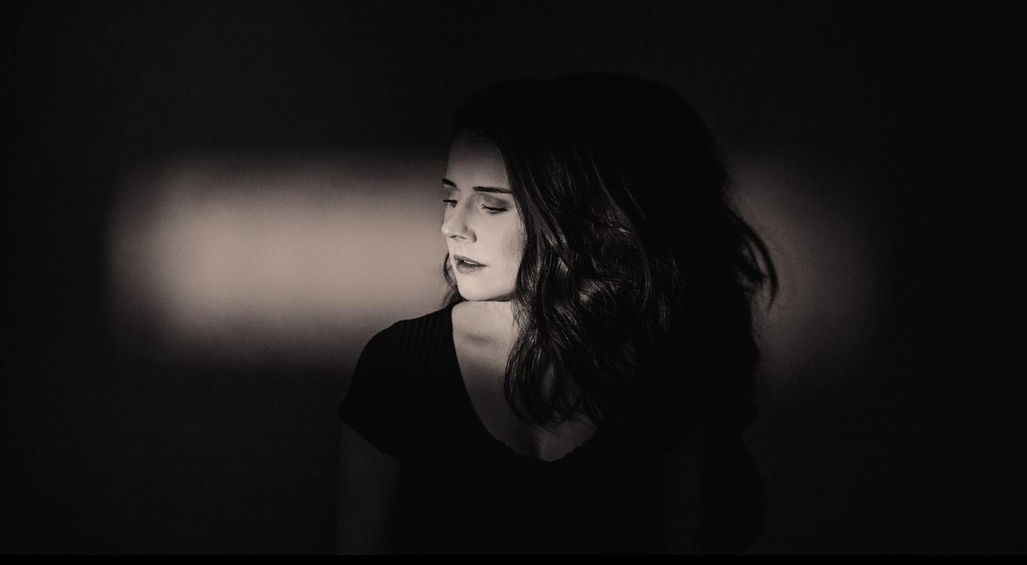 Hannah against a dark background, a strip of light highlighting her face