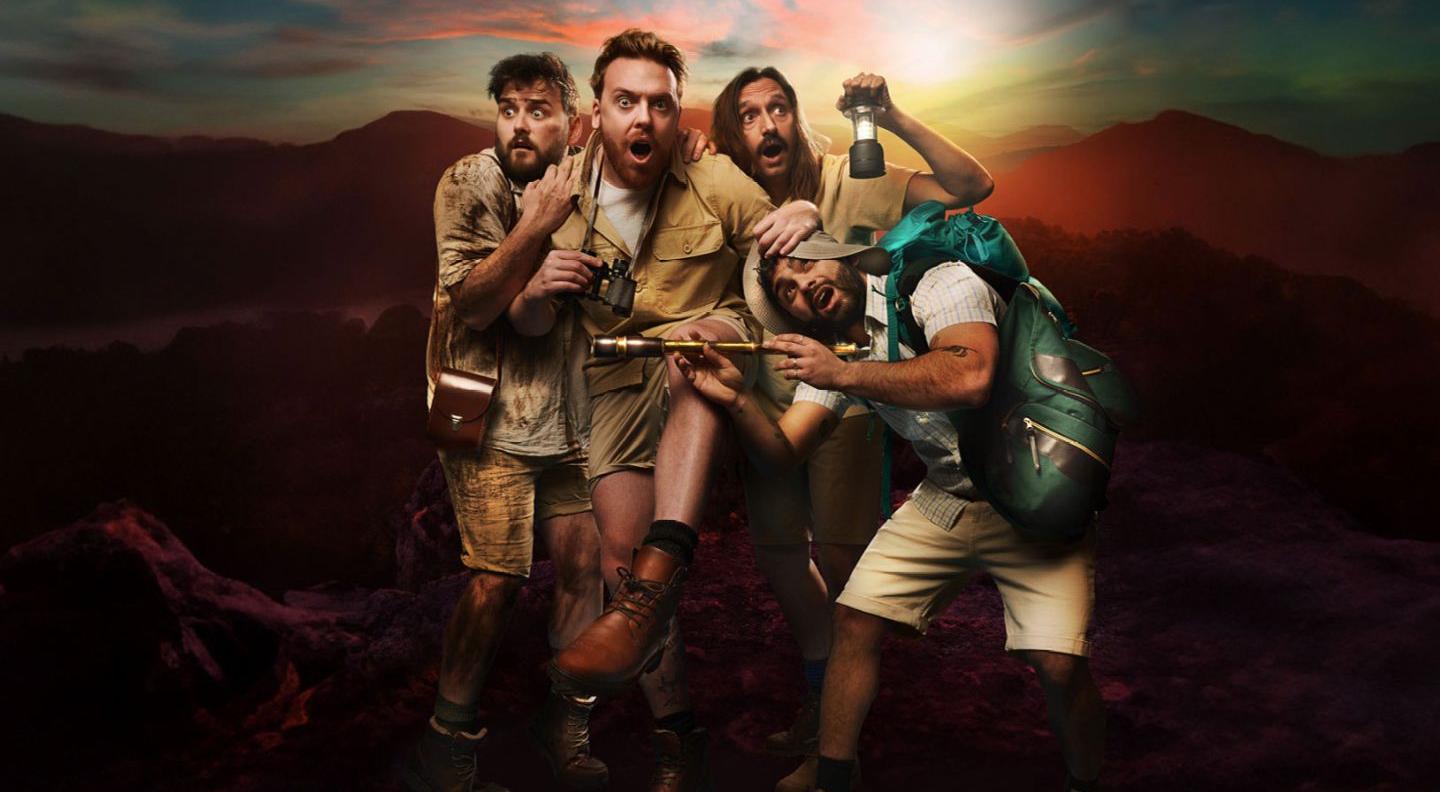 four young men dressed in adventure clothes cower away from the camera, looking afraid