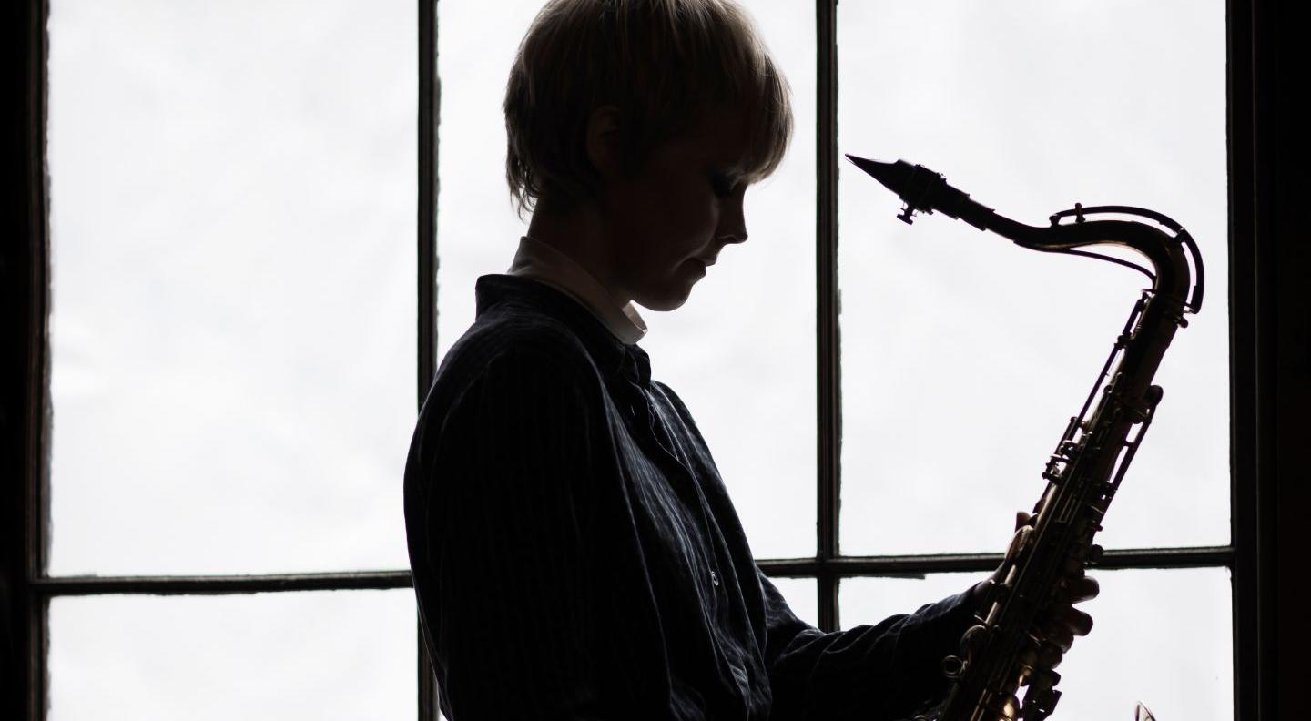 a silhouette of saxophonist Helena Kay