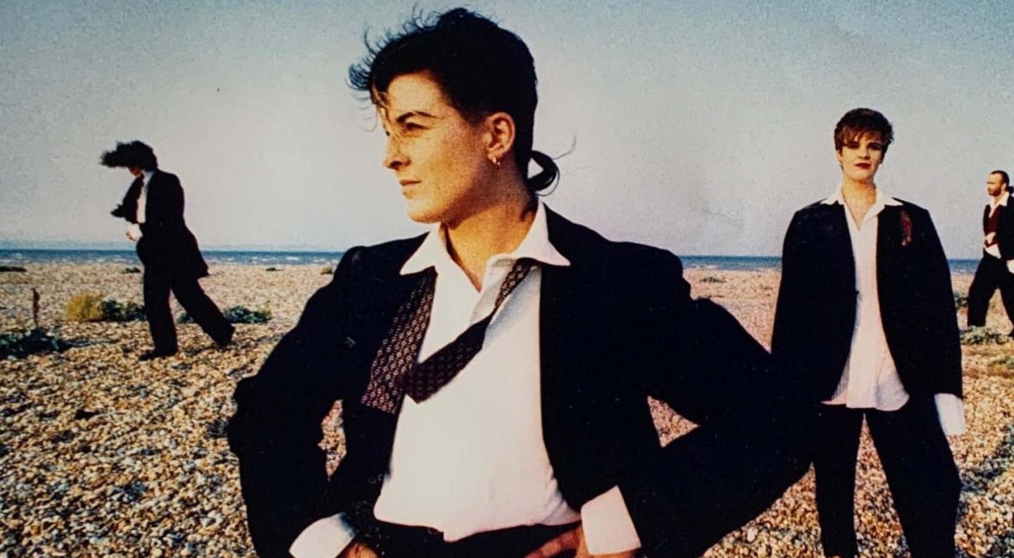 HORSE standing with their hands on their hips on a beach wearing a suit