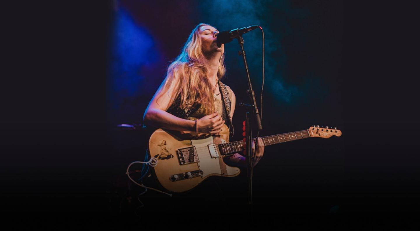 Joanne Shaw Taylor playing guitar and singing into a microphone on stage