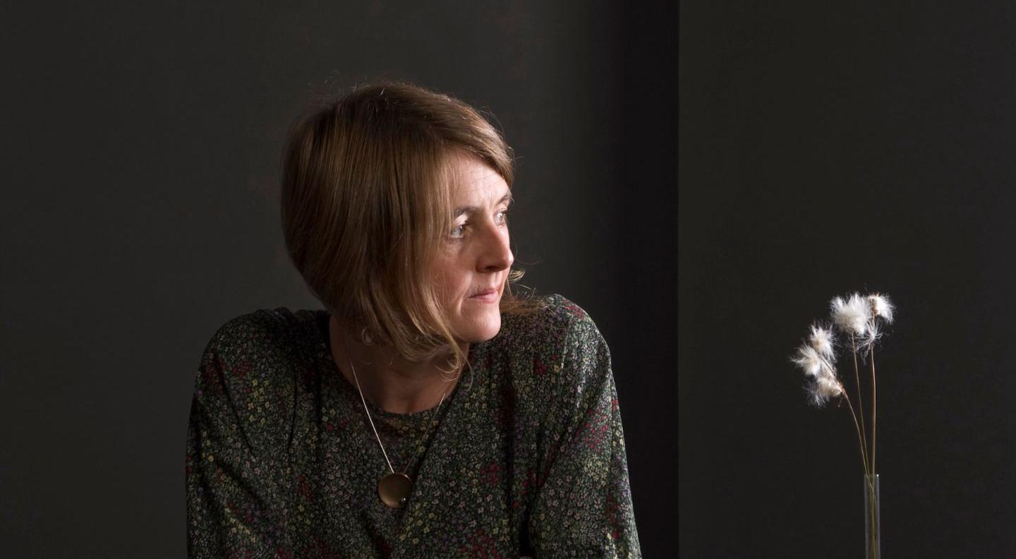 Karine Polwart sits looking off to her left against a grey background