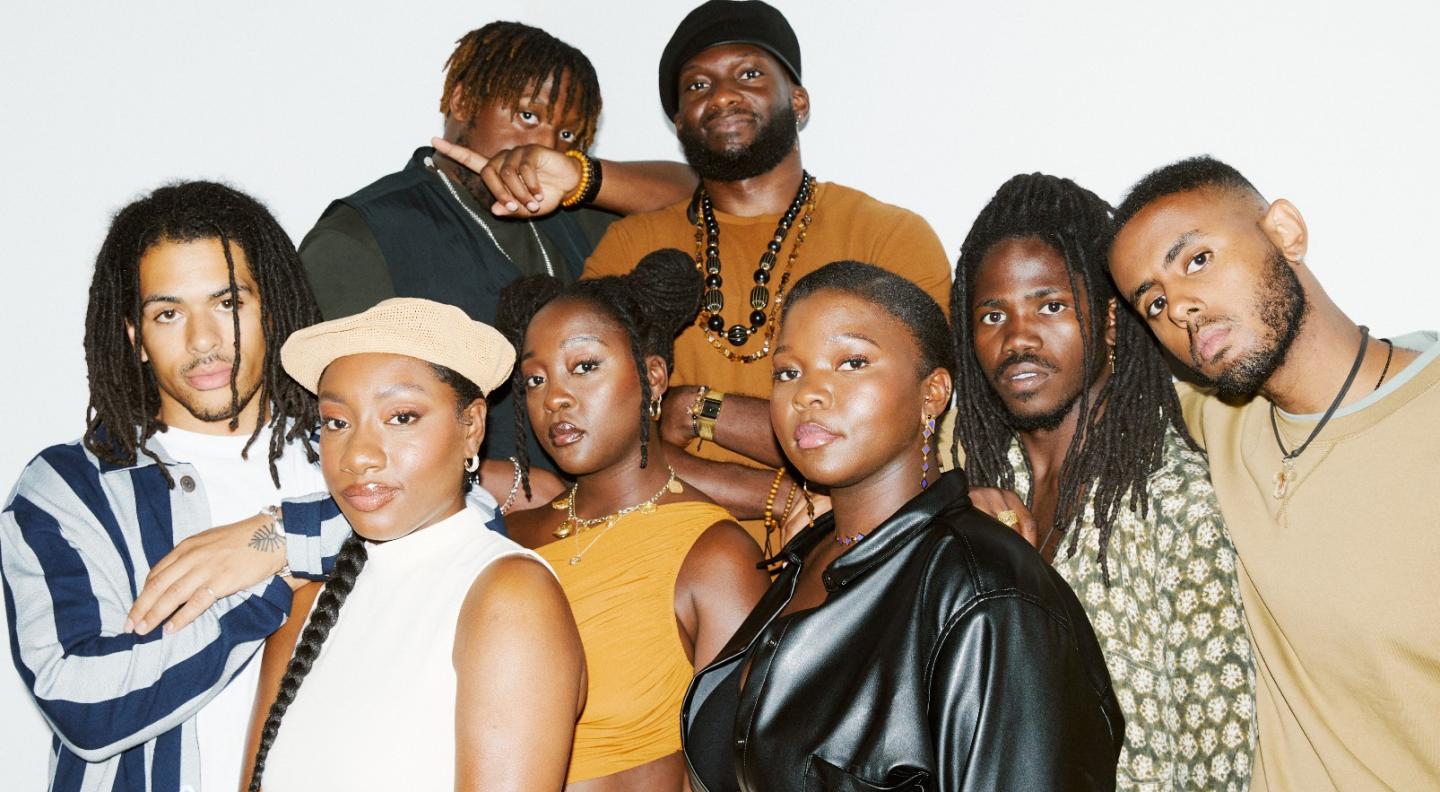 The eight members of Kokoroko stand in a group looking at the camera. Image credit Danny Kasirye