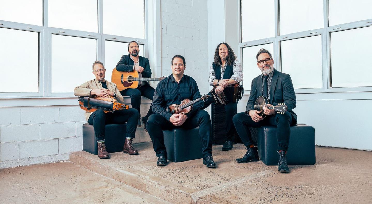 The five members of Le Vend du Nord sitting on black boxes holding their instruments