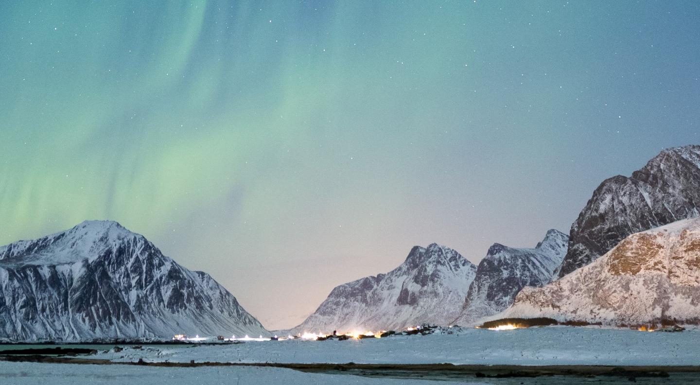 An Arctic landscape with the green glow of the aurora borealis in the sky