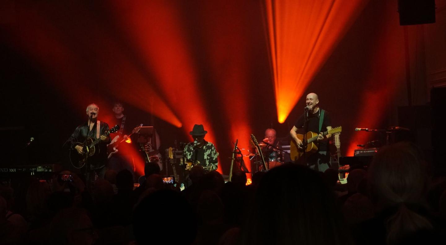 Lindisfarne performing on stage with red lighting 