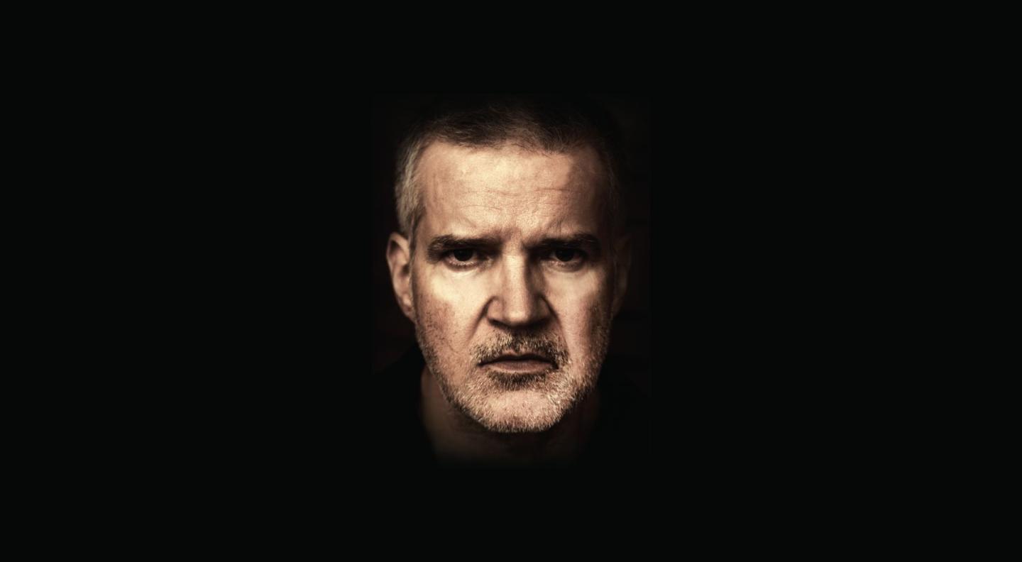 Lloyd Cole in front of a black background