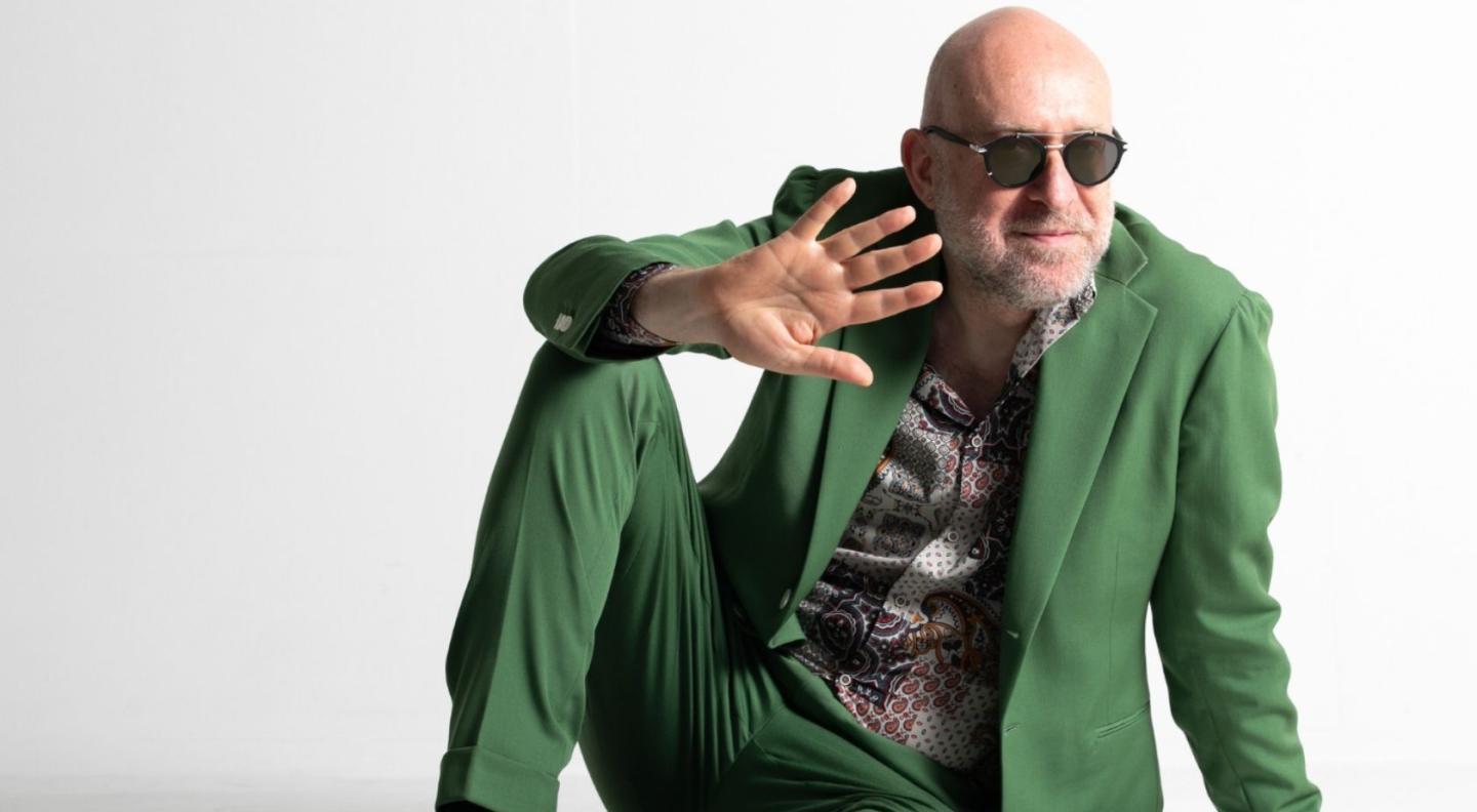 Mario Biondi sitting cross legged in a green suit