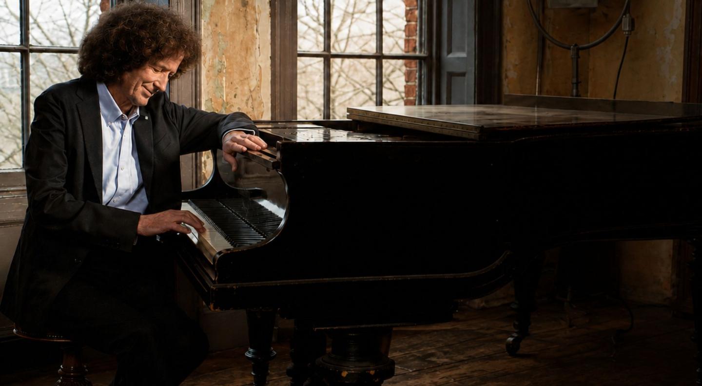 Gilbert O'Sulivan sits at a grand piano