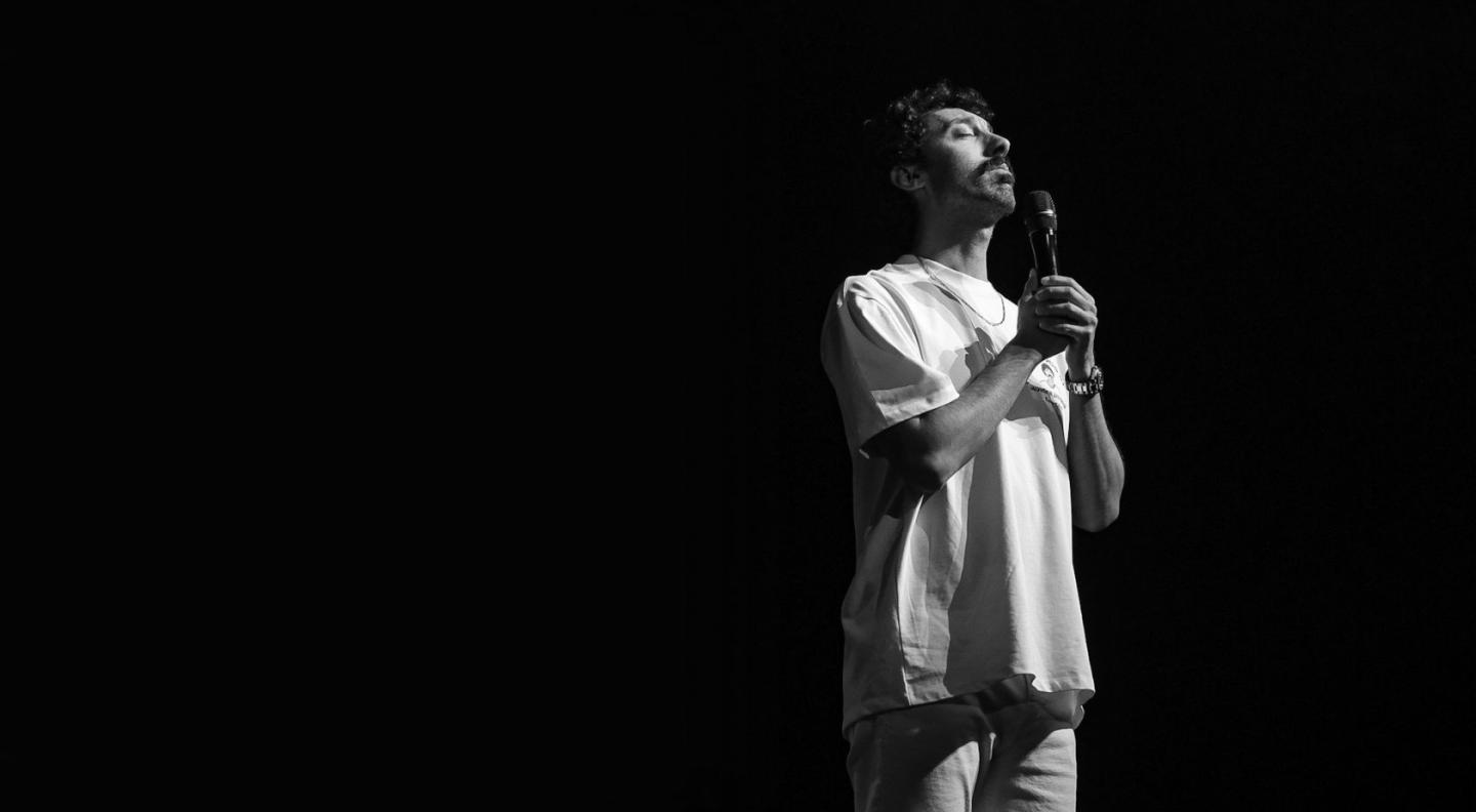 an image of Morgan Jay holding a microphone on an otherwise dark stage