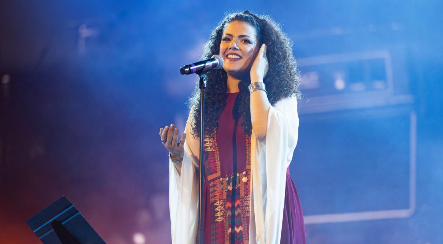 Nai Barghouti singing into a microphone