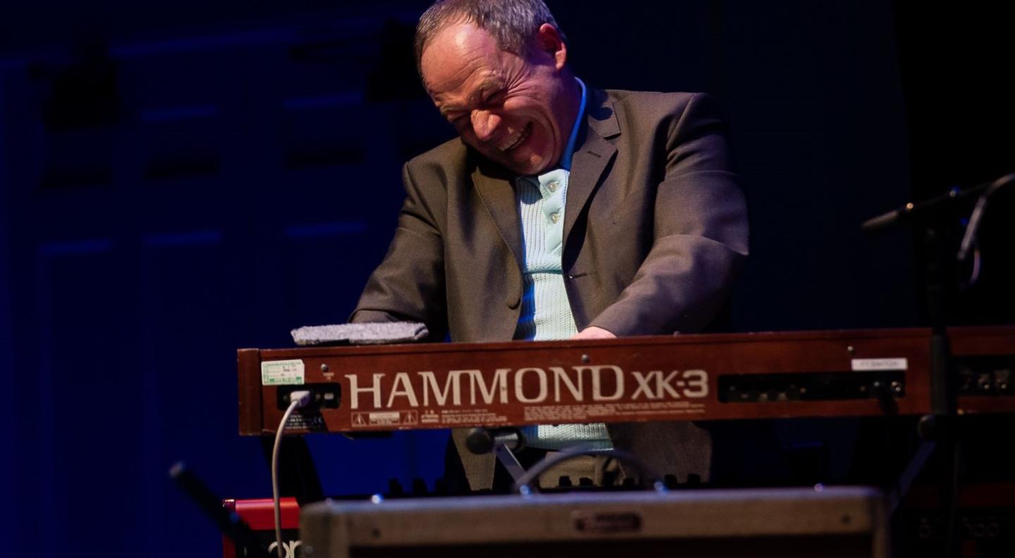 An image of a older white man  with a joyful expression on his face playing the Hammond organ
