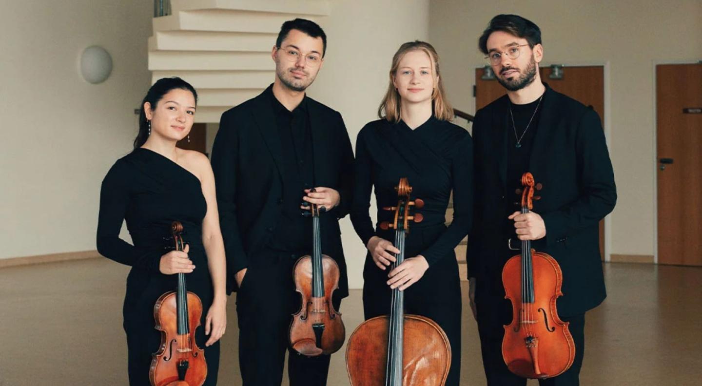 The four members of the NOVO quartet, two men and two women, wearing concert black outfits, holding their instruments