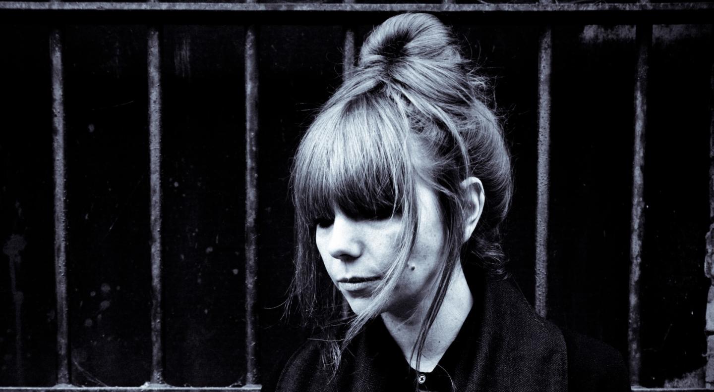 Poppy Ackroyd is photographed in black and white against a dark wall