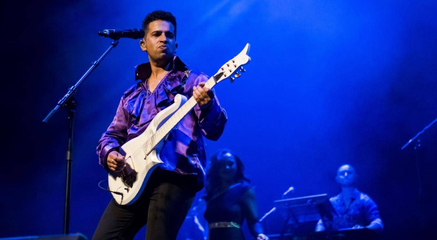 Performer Jimi Love plays a white guitar in the fashion of Prince