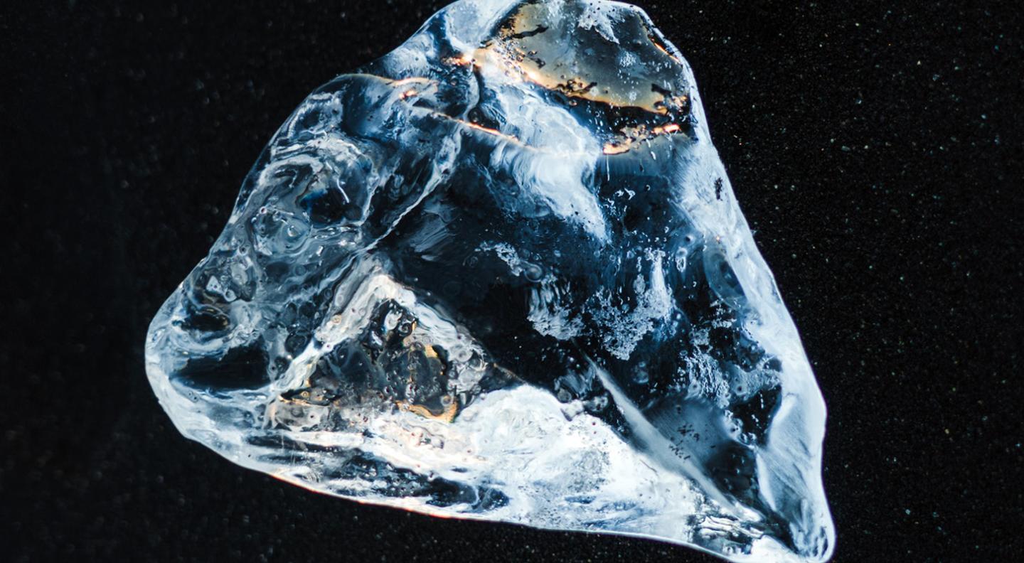 An abstract image of a triangular textured block of ice floating in a black, starry sky