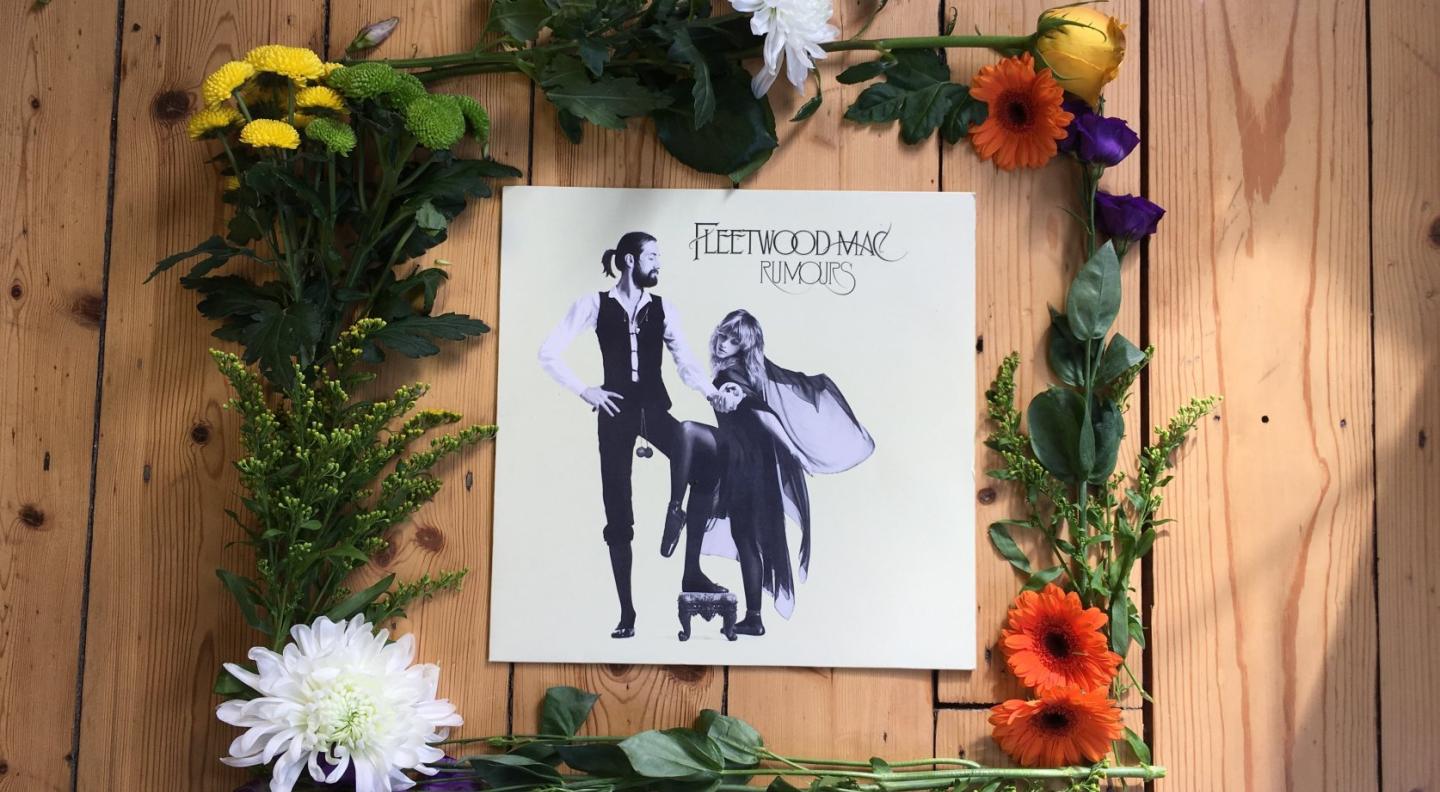 an image of the Rumours album on vinyl, surrounded by flowers on a wooden table